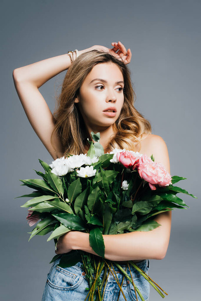 young, charming woman posing with bouquet isolated on grey - Foto, Bild