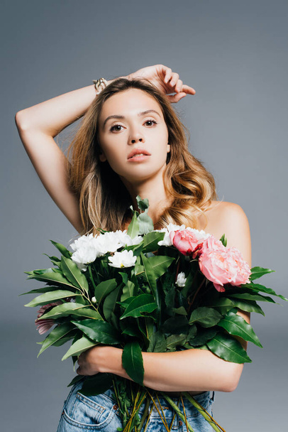seductive young woman with flowers looking at camera isolated on grey - Foto, afbeelding