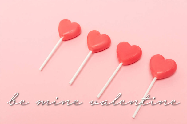 heart shaped lollipops near be mine valentine lettering on pink background - Photo, Image
