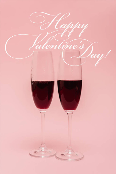 red wine in glasses near happy valentines day lettering on pink - Foto, Bild
