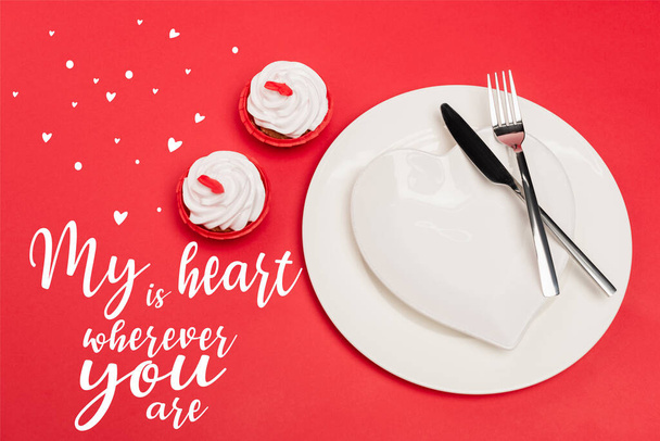 top view of cupcakes near plates with cutlery and my heart is wherever you are lettering on red background - Fotografie, Obrázek