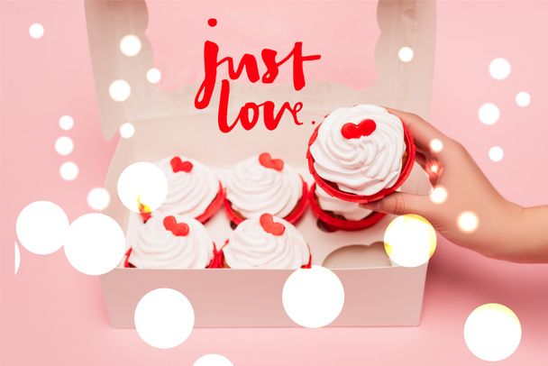 cropped view of woman holding valentines cupcake near box and just love lettering on pink background - Valokuva, kuva
