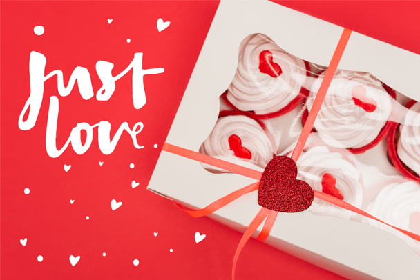 Вид сверху коробки с вкусными кексами рядом с любовной линией на красном - Фото, изображение