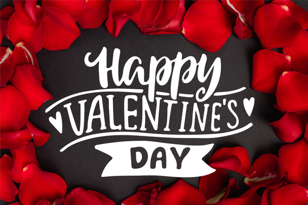 vista superior de feliz día de San Valentín letras en marco con pétalos de rosa roja en negro - Foto, imagen
