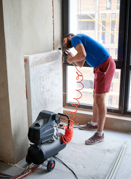 Loodgieter vullen leidingen met lucht te inspecteren op lekken in nieuwe installatie, met behulp van luchtcompressor tijdens het controleren van gas dichtheid van verwarmingssysteem. Begrip woningrenovatie en gasdichtheidstests. - Foto, afbeelding