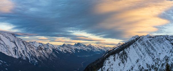Die schneebedeckte Bergkette Mount Rundle in der schönen Abenddämmerung. Himmel aus rot-rosa Wolken im Hintergrund. Banff-Nationalpark im Winter, kanadische Rockies. Schöne Naturkulisse. - Foto, Bild