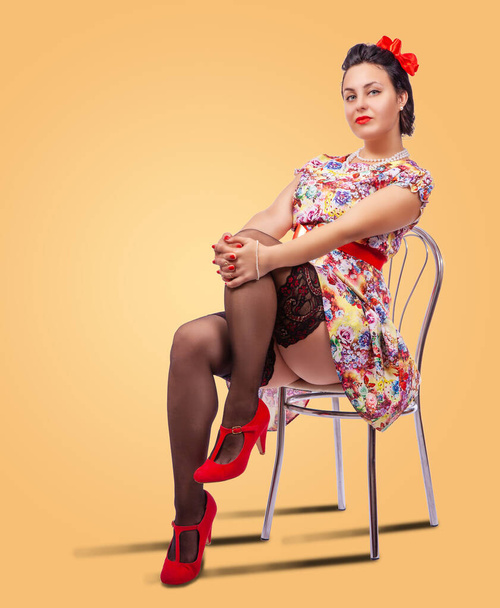 Nuori brunette nainen poseeraa istuu tuolilla studiossa. pinup-tyyli - Valokuva, kuva