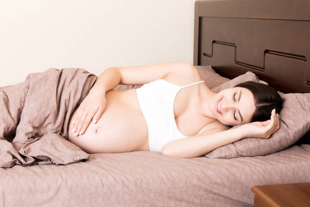 красива молода вагітна жінка лежить у ліжку, вид зверху. дівчина страждає від того, що її чоловік залишив її
. - Фото, зображення