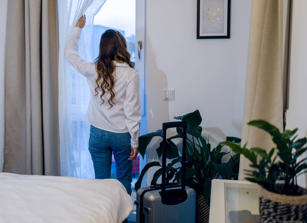 Young woman on the road arrives in her hotel room - Foto, Bild