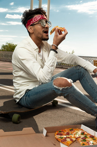 ピザを食べてる若い男。外だ。選択的焦点 - 写真・画像