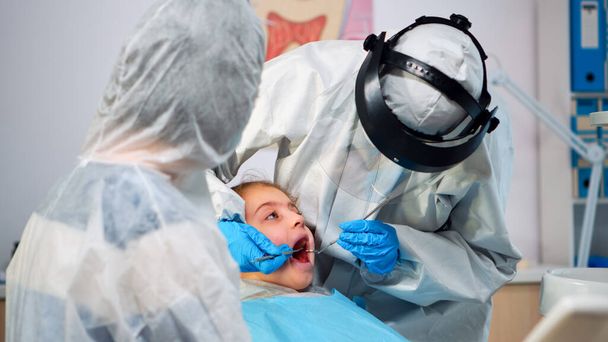 Close up of dentist in coverall examining girl patient in new normal dental unit - Photo, Image