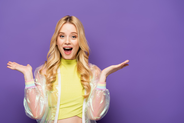 happy blonde young woman in colorful outfit on purple background - Valokuva, kuva
