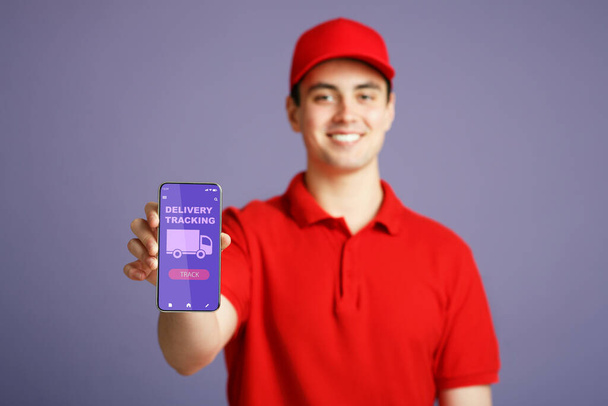 Kurýr muž držící mobilní telefon s aplikací pro sledování doručení - Fotografie, Obrázek