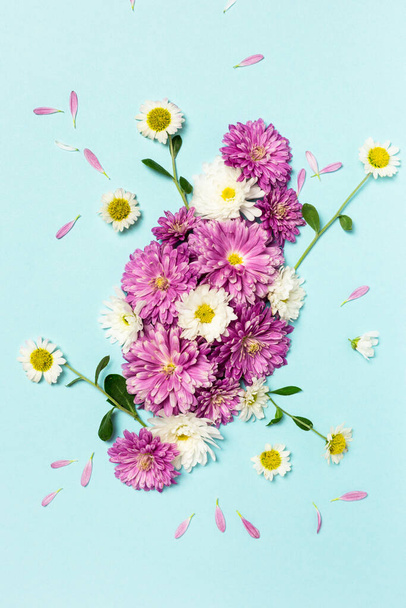 Virágok összetétele. Kreatív elrendezés készült fehér és lila virágok pasztell kék háttér. Lapos fekvés. Tavaszi minimális koncepció. - Fotó, kép