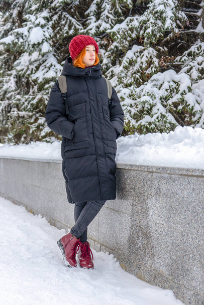 Teen girl wearing casual clothes walking on snow covered city street in winter. Young lady spending weekend in city. Urban vacation, winter holiday, slow life. Fashionable outfit, youth fashion. - Foto, Imagen