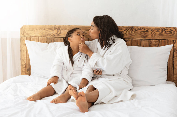 Piękna afrykańska matka i córka relaks w szlafrokach na łóżku i więzi - Zdjęcie, obraz
