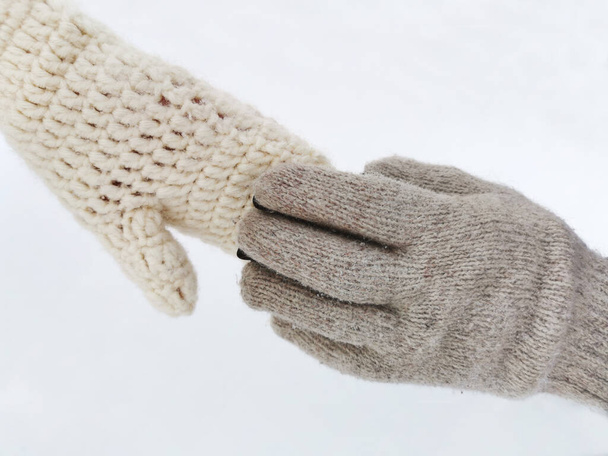 Couple holding hands in gloves in winter season on the background of white snow - Fotografie, Obrázek