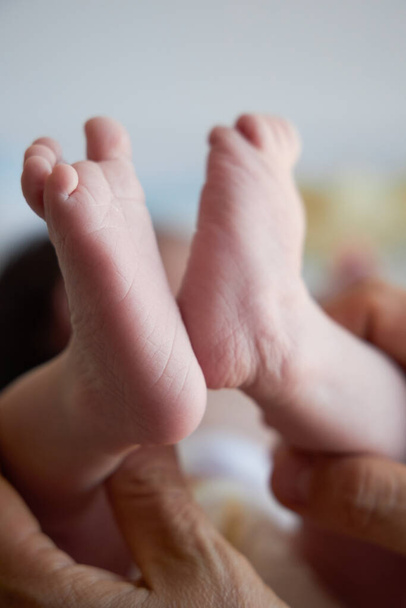 Kleine Füße eines Neugeborenen aus nächster Nähe. Die ersten Tage im Leben eines Babys. Vertikaler Schuss. - Foto, Bild