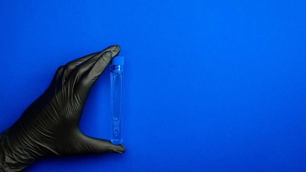 Jeringa aislada. Médico mano en guante médico mantenga la probeta o el frasco para la protección del virus de la gripe y coronavirus. Vacuna covid aislada en azul. Concepto lucha contra el virus covid-19 - Foto, imagen