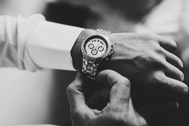Black and white photo, man in a shirt adjusts the watch on his arm. Close up of businessman using watch. - Foto, immagini