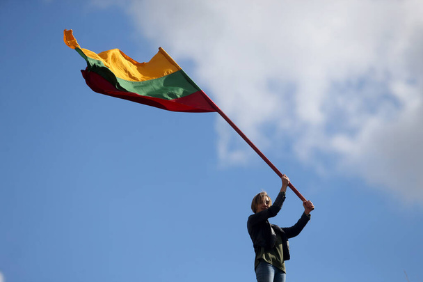 Νεαρή ευτυχισμένη γυναίκα με λιθουανική σημαία, φόντο στον ουρανό - Φωτογραφία, εικόνα