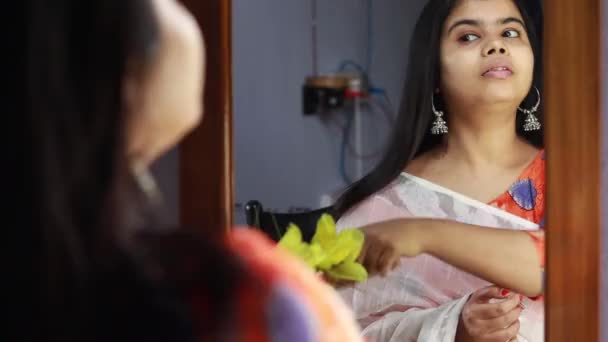 uma bela mulher indiana em branco saree pentear o cabelo na frente do espelho com rosto sorridente - Filmagem, Vídeo