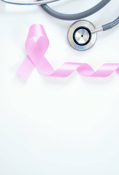 Pink ribbon and stethoscope on white background, closeup. Breast cancer awareness concept - Фото, зображення