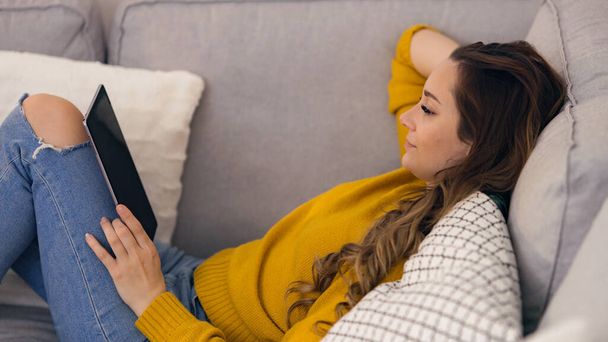 Young woman with her tablet computer on the couch - Foto, Imagem