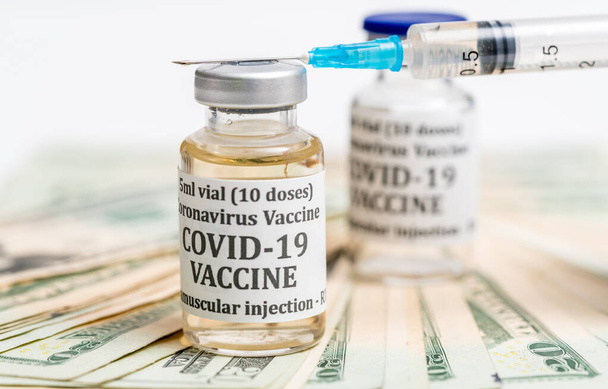 Close-up van de injectiespuit op de fles Covid-19 vaccin met contant geld - Foto, afbeelding
