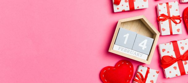 あなたのデザインのための空のスペースとカラフルな背景にギフトボックス、木製のカレンダーと赤いテキスタイルの心の休日の組成。2月14日。バレンタインデーのコンセプトのトップビュー. - 写真・画像