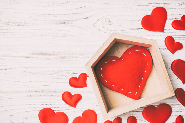 Vista superior del corazón rojo en una casa decorada con pequeños corazones sobre fondo de madera. Día de San Valentín. Hogar dulce hogar concepto. - Foto, imagen