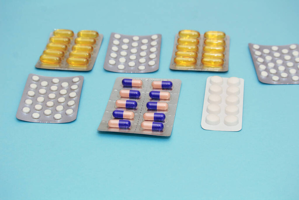 Διάφορα πολύχρωμα χάπια, ιχθυέλαιο και βιταμίνες σε μπλε φόντο. Έννοια υγειονομικής περίθαλψης - Φωτογραφία, εικόνα