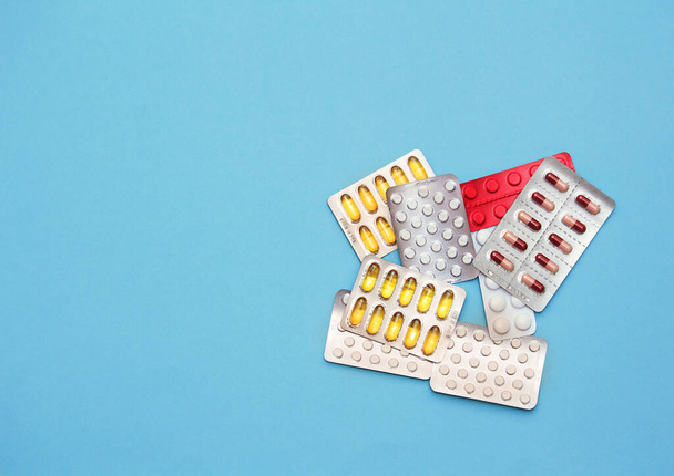 Erilaisia monivärisiä pillereitä ja vitamiineja sinisellä taustalla. Terveydenhuollon käsite - Valokuva, kuva