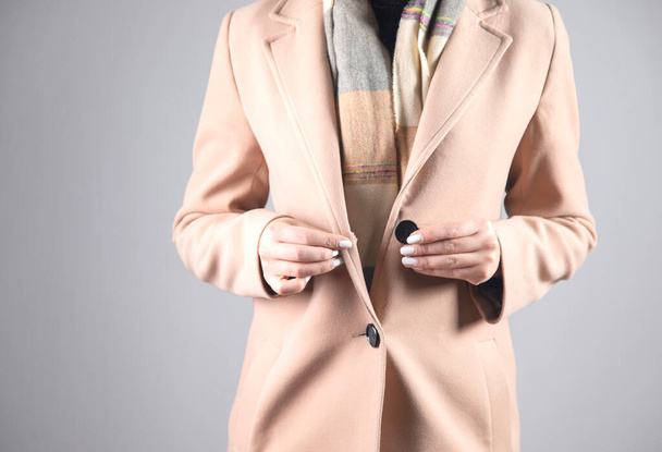 young woman with coat button on grey background - Foto, immagini