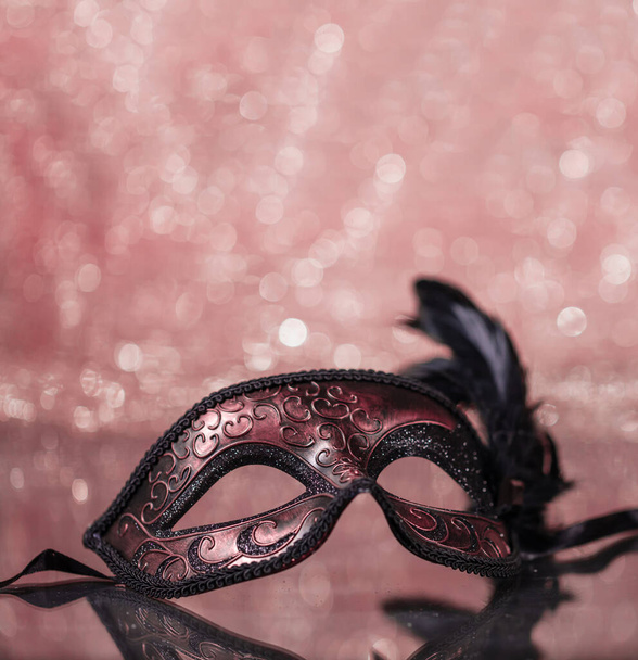 カーニバルマスク。ピンクのボケの背景に羽を持つ装飾の高級菜食主義者のマスク。パーティー、マジックショー、オペラ、フェスタ、演劇、フェスティバルのための神秘的な仮面舞踏会。コピースペース,反射. - 写真・画像