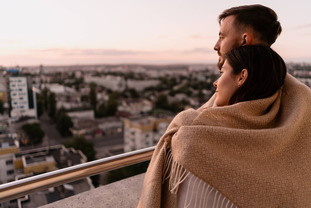 Uomo e donna sul balcone al tramonto in città - Foto, immagini