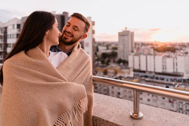 Мужчина и женщина на балконе на закате в городе - Фото, изображение