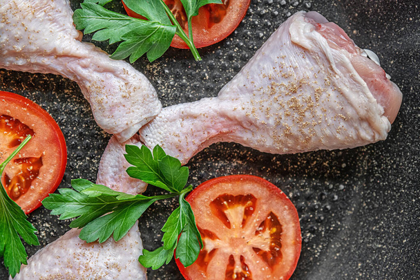 Patas frescas de pollo crudo sazonadas con especias, perejil y tomates en una sartén - Foto, Imagen