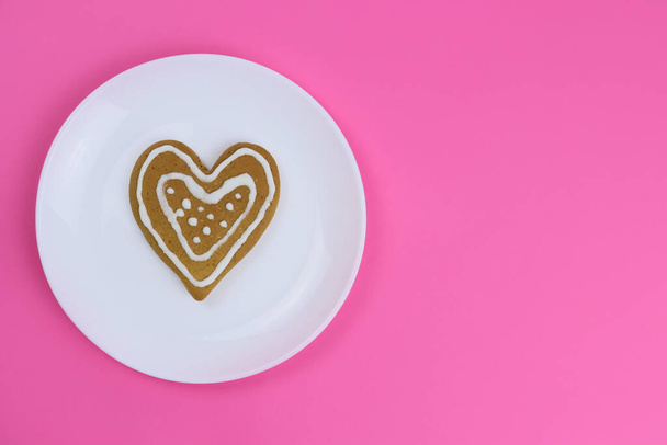 Пряничное печенье сердца в белой тарелке на розовом фоне - Фото, изображение