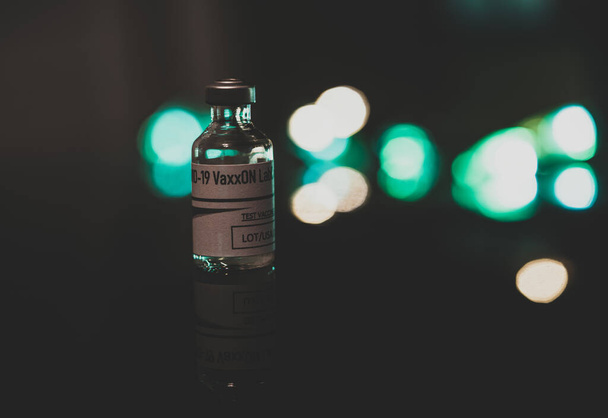 covid 19 butelka szczepionki na odblaskowym czarnym blacie z abstrakcyjnym tłem - Zdjęcie, obraz