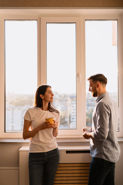 Un hombre y una mujer beben té cerca de la ventana - Foto, imagen
