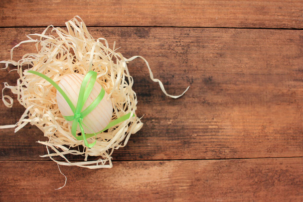Чисте дерев'яне пасхальне яйце для малювання або декорування в гнізді на дерев'яному тлі. Краєвид - Фото, зображення