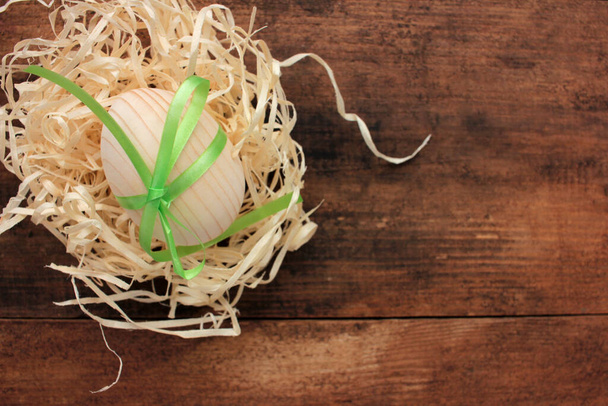 Uovo di Pasqua in legno bianco per dipingere o decoupage in nido su fondo legno. Vista dall'alto - Foto, immagini