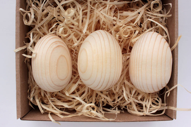 Blanke Holzeier zum Bemalen oder Decoupage in Geschenkbox. Ostereier in einem Korb auf einem Holztisch. Ansicht von oben - Foto, Bild