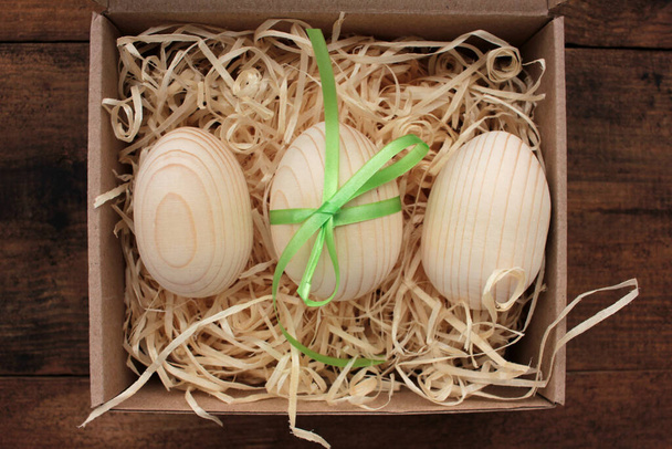 Üres fából készült tojás festésre vagy dekoupage ajándékdobozban. Húsvéti tojás egy kosárban a fa asztalon. Felülnézet - Fotó, kép
