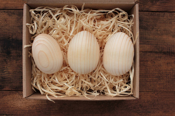 Ovos de madeira em branco para pintura ou decoupage em caixa de presente. Ovos de Páscoa em uma cesta na mesa de madeira. Vista superior - Foto, Imagem