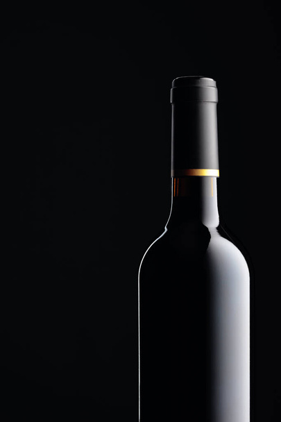 Неоткрытая бутылка красного вина на черном фоне. Копирование пространства. - Фото, изображение