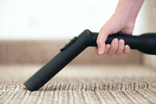 Woman is cleaning the furniture from the dust by the vacuum cleaner close up. - Foto, Imagem