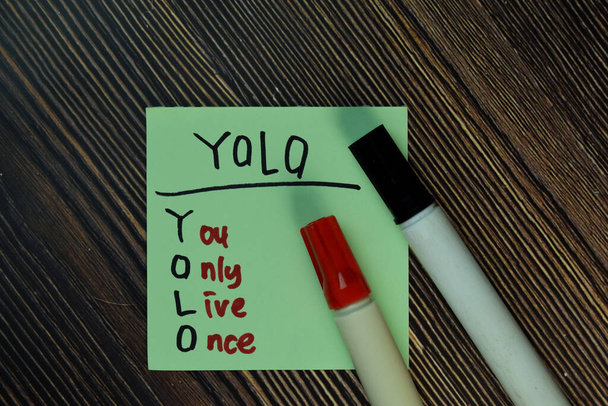 YOLO - Du lebst nur einmal Schreibe auf klebrige Zettel isoliert auf Holztisch. - Foto, Bild
