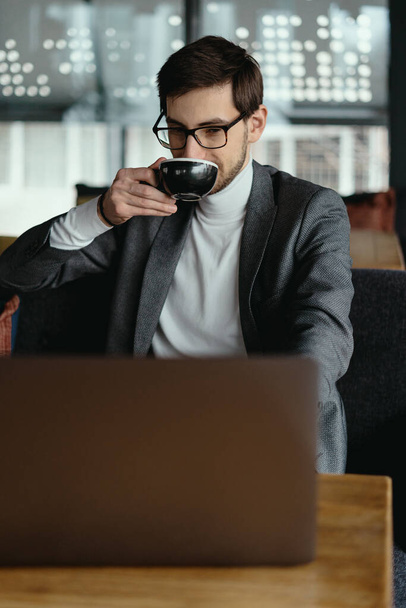 Erfolgreicher Geschäftsmann arbeitet beim Kaffeetrinken am Laptop - Foto, Bild